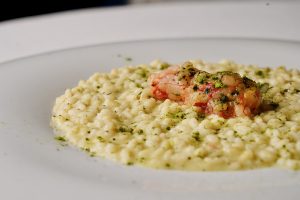 risotto cacio e pepe cotto nel brodo di ricciola con tartare di gambero rosso del Mozambico, lime e the macha insieme al Buttafuoco Storico